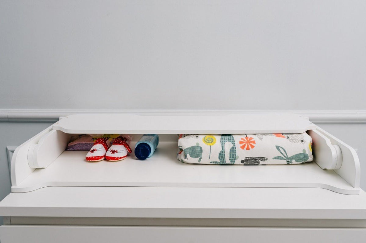 8. White changing table top with baby shoes, bottle, and colorful mat in a nursery