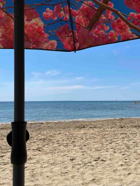 3. Close-up of cherry beach and terrace parasol with red floral pattern against a sandy beach and ocean view