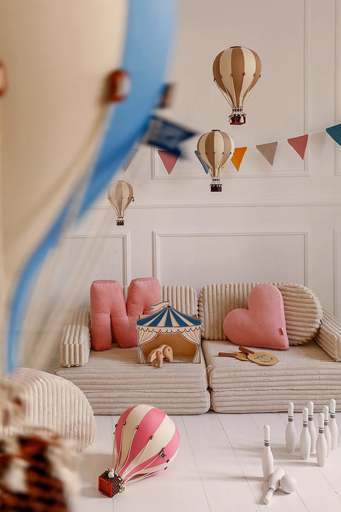 5. Playroom with blue and white circus puppet theater on sofa, surrounded by colorful cushions and hot air balloon decorations
