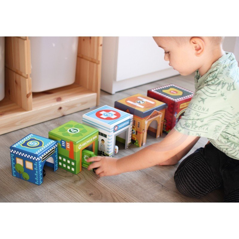 7. Boy playing with colorful city-themed puzzle cubes and wooden vehicles on a wooden floor