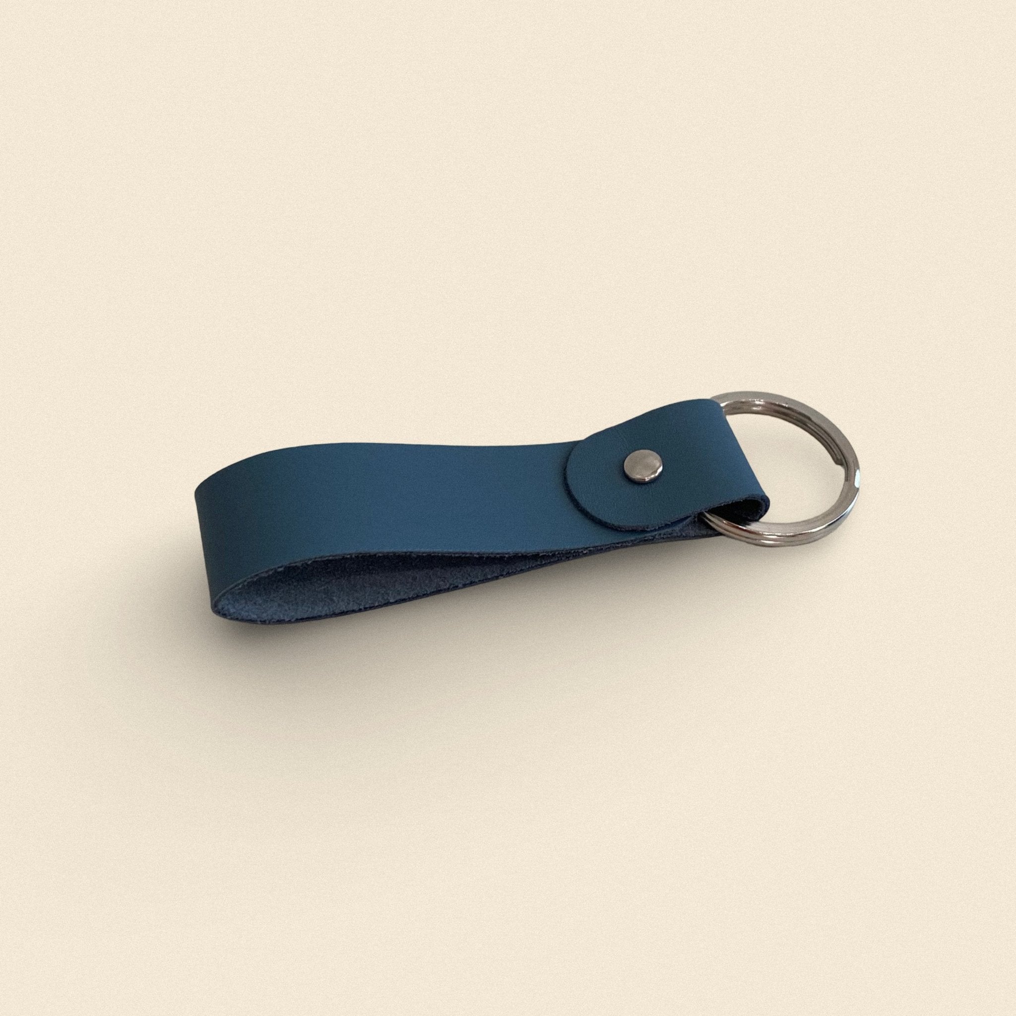 18. Blue-gray handmade leather keychain by Yoru with metal ring on beige background