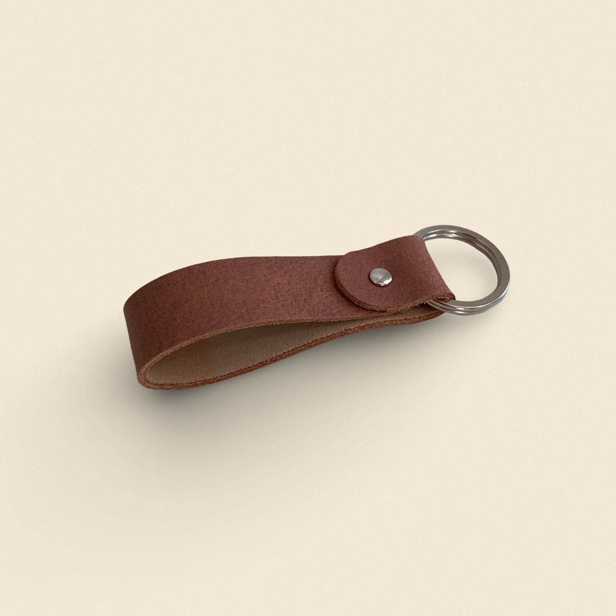 16. Light brown handmade leather keychain by Yoru with metal ring on beige background