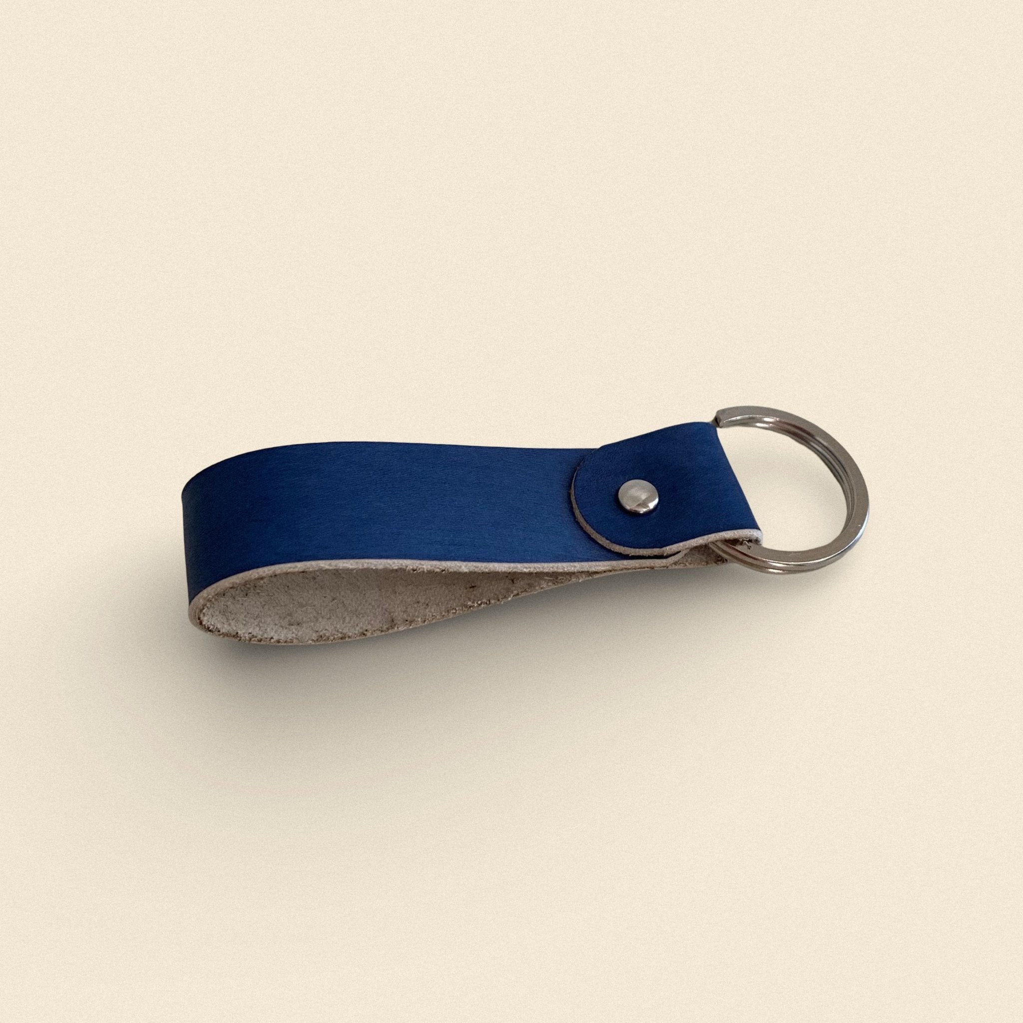 14. Navy blue handmade leather keychain by Yoru with metal ring on beige background