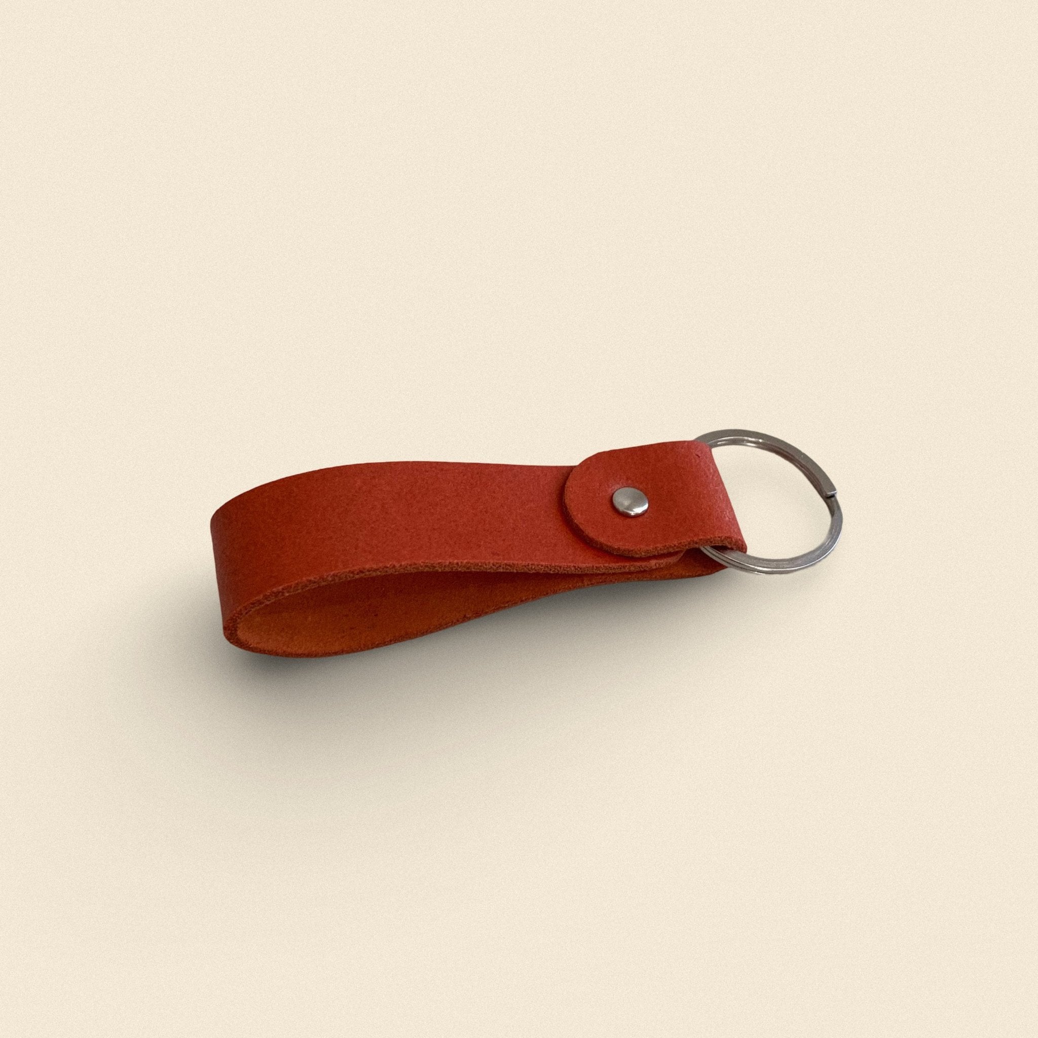 15. Orange handmade leather keychain by Yoru with metal ring on beige background
