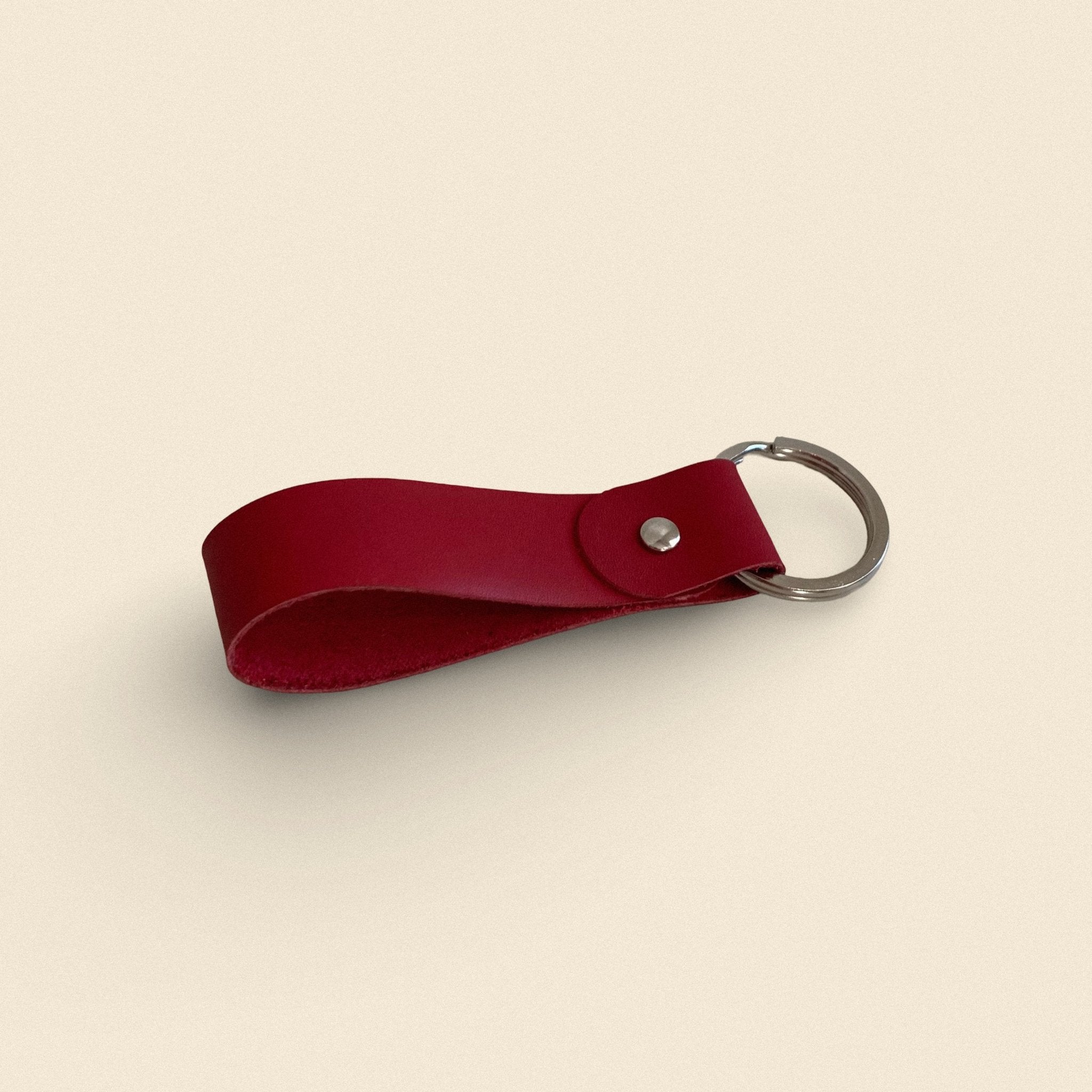 13. Red handmade leather keychain by Yoru with metal ring on beige background