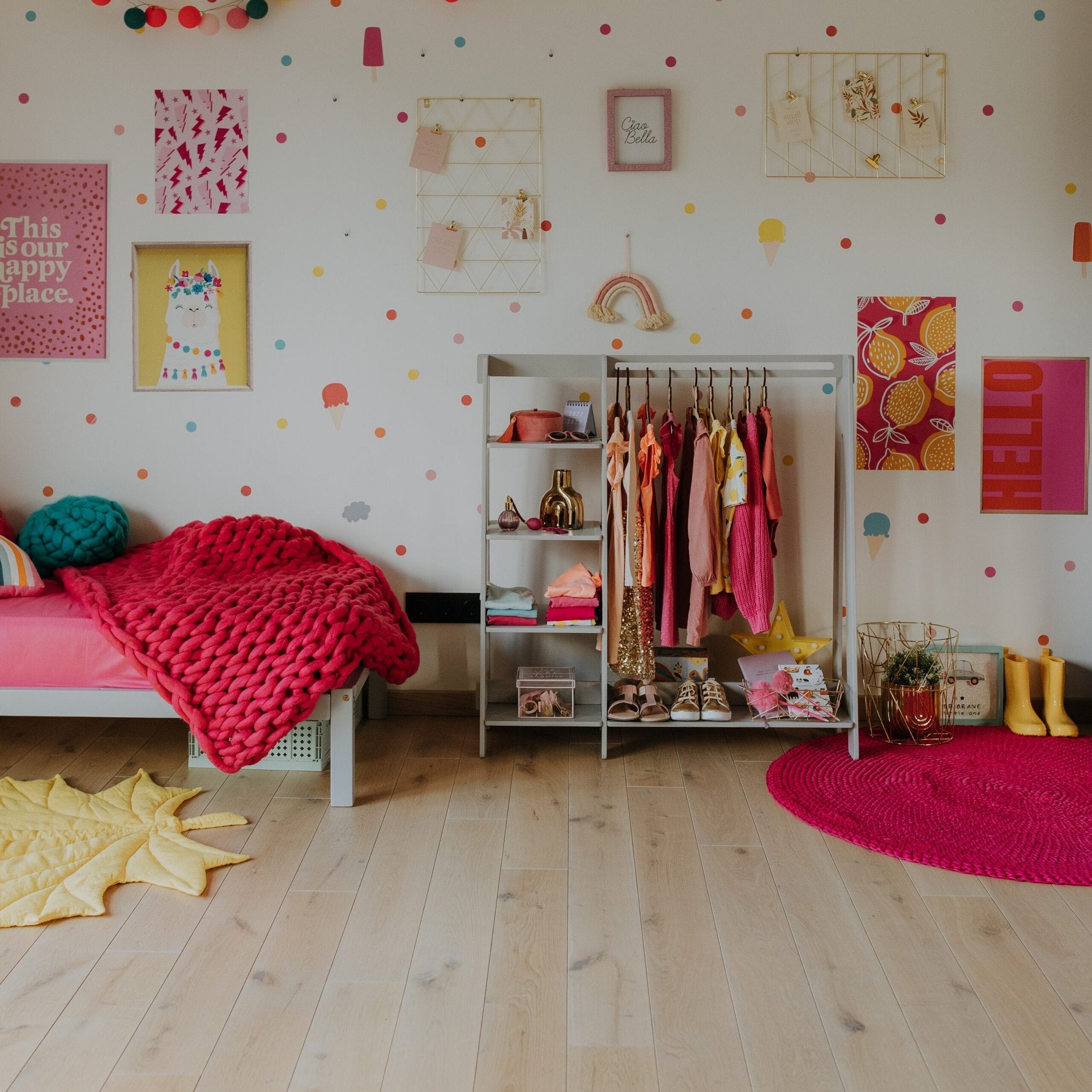 16. Children's room with grey clothing rack holding colorful toddler clothes and toys