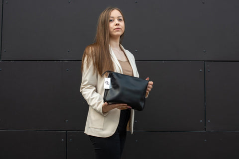 1. Woman holding Zelma Kraft large black leather cosmetic bag, showcasing elegant design and size