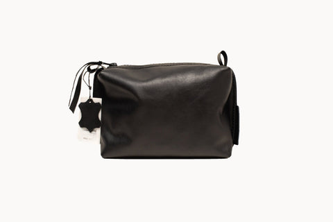 5. Studio image of Zelma Kraft black leather cosmetic bag with zipper closure and tag