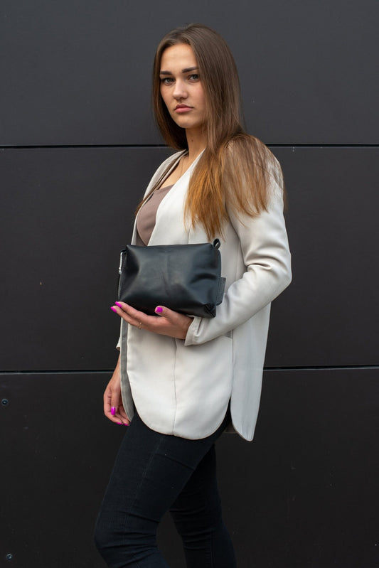 1. Woman holding Zelma Kraft black leather cosmetic bag, showcasing compact design and elegant style
