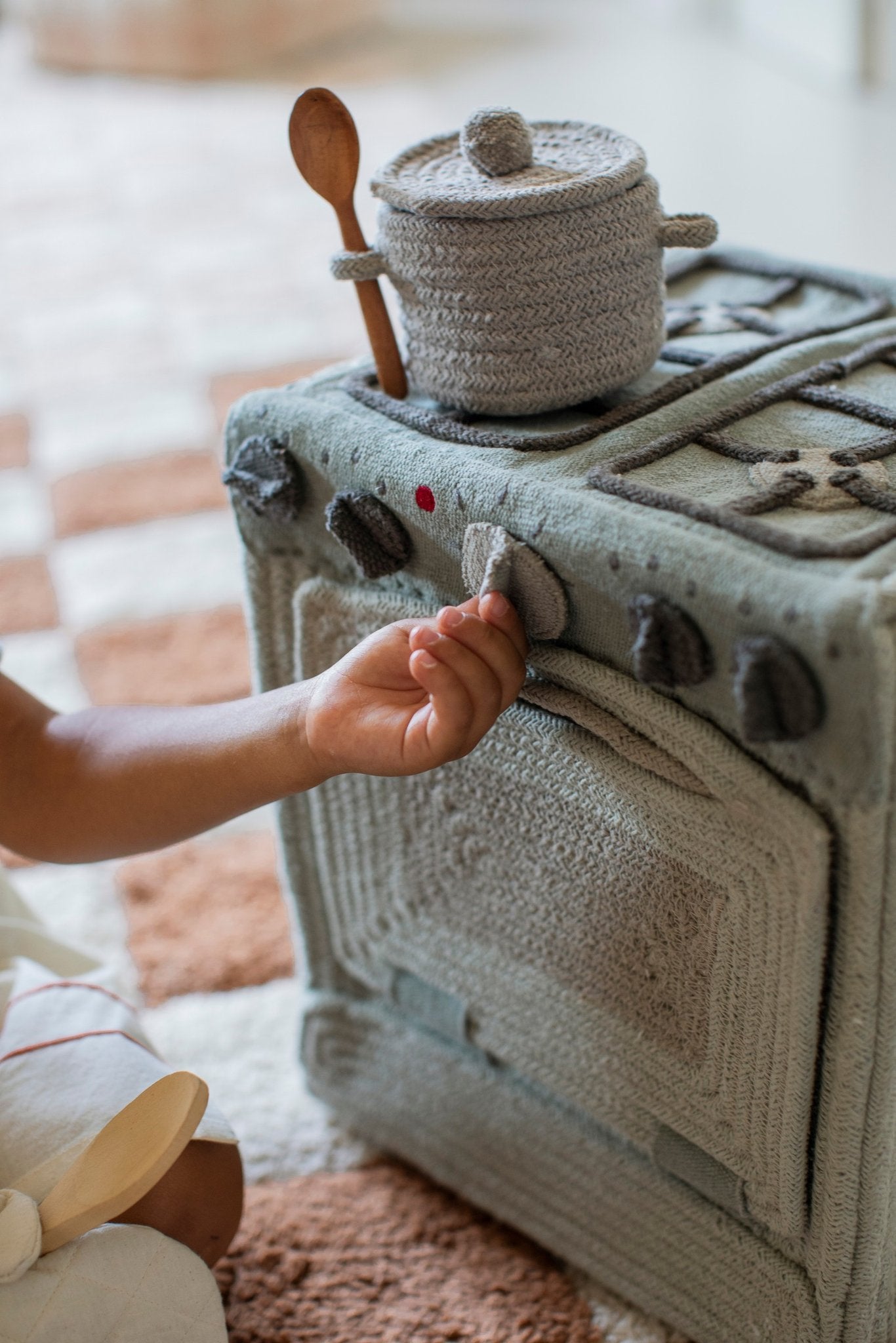 7. Child's hand turning knob on Lorena Canals blue sage textile toy stove