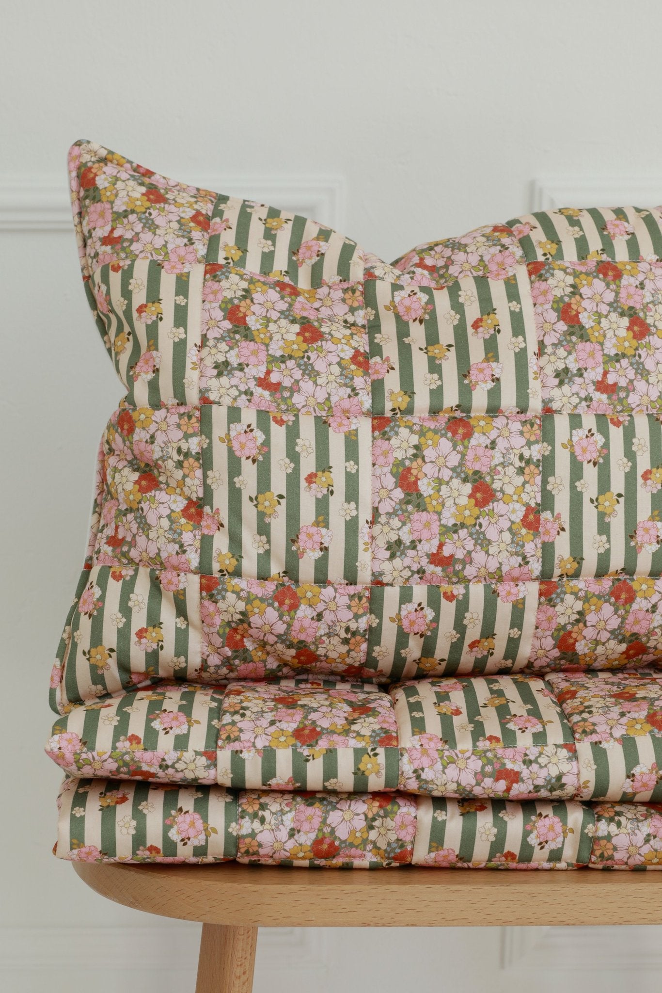 1. Studio shot of Moi Mili cotton quilted patchwork blanket and pillow set in green garden pattern on wooden chair