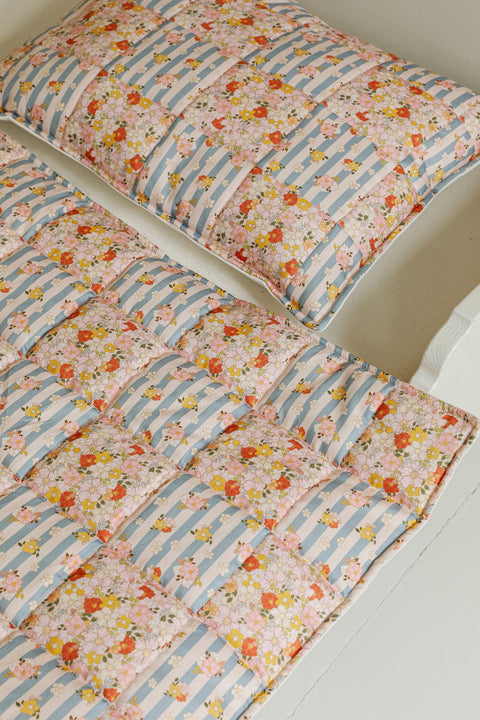 3. Detail of Moi Mili cotton quilted patchwork blanket and pillow on bed showing floral and striped design