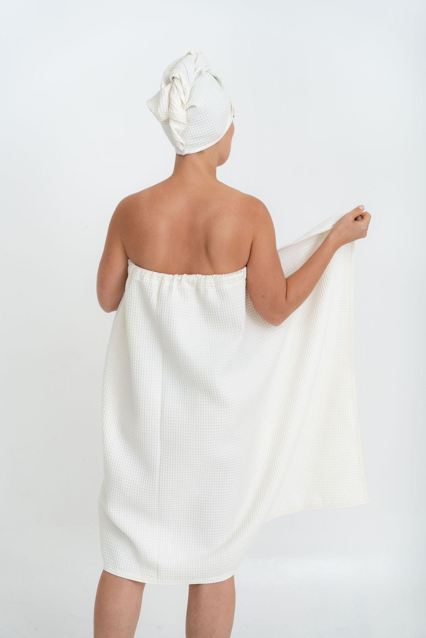1. Woman in white cotton waffle sauna wrap with matching head wrap, shown from back in studio setting