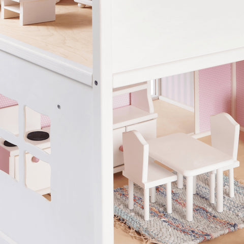 2. Close-up of dollhouse interior with white wooden furniture set on a woven rug, showing pink wallpaper and window detail
