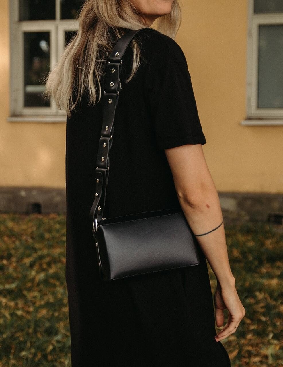 1. Woman wearing black dress with Stella Soomlais black crossbody bag over shoulder in outdoor setting