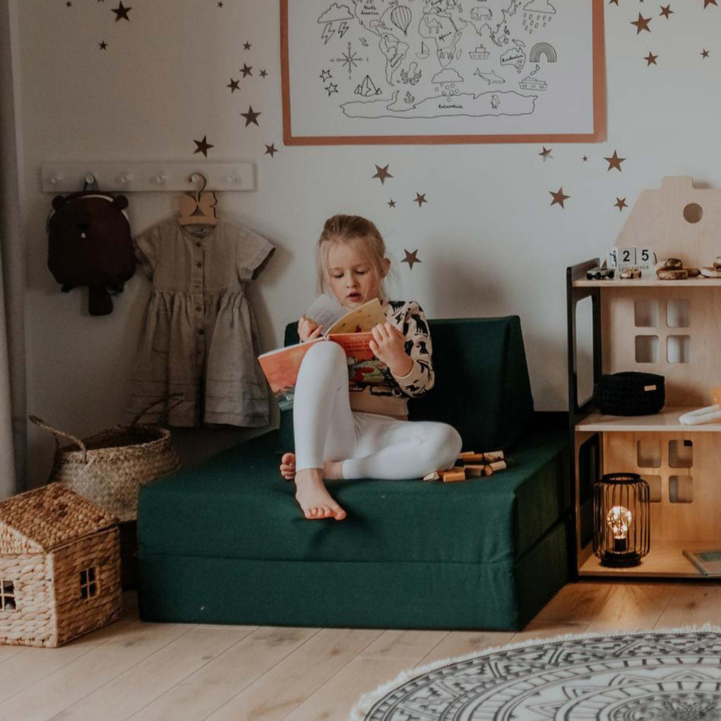 2. Child reading on Monboxy deep green play mattress set in a cozy room with star decorations