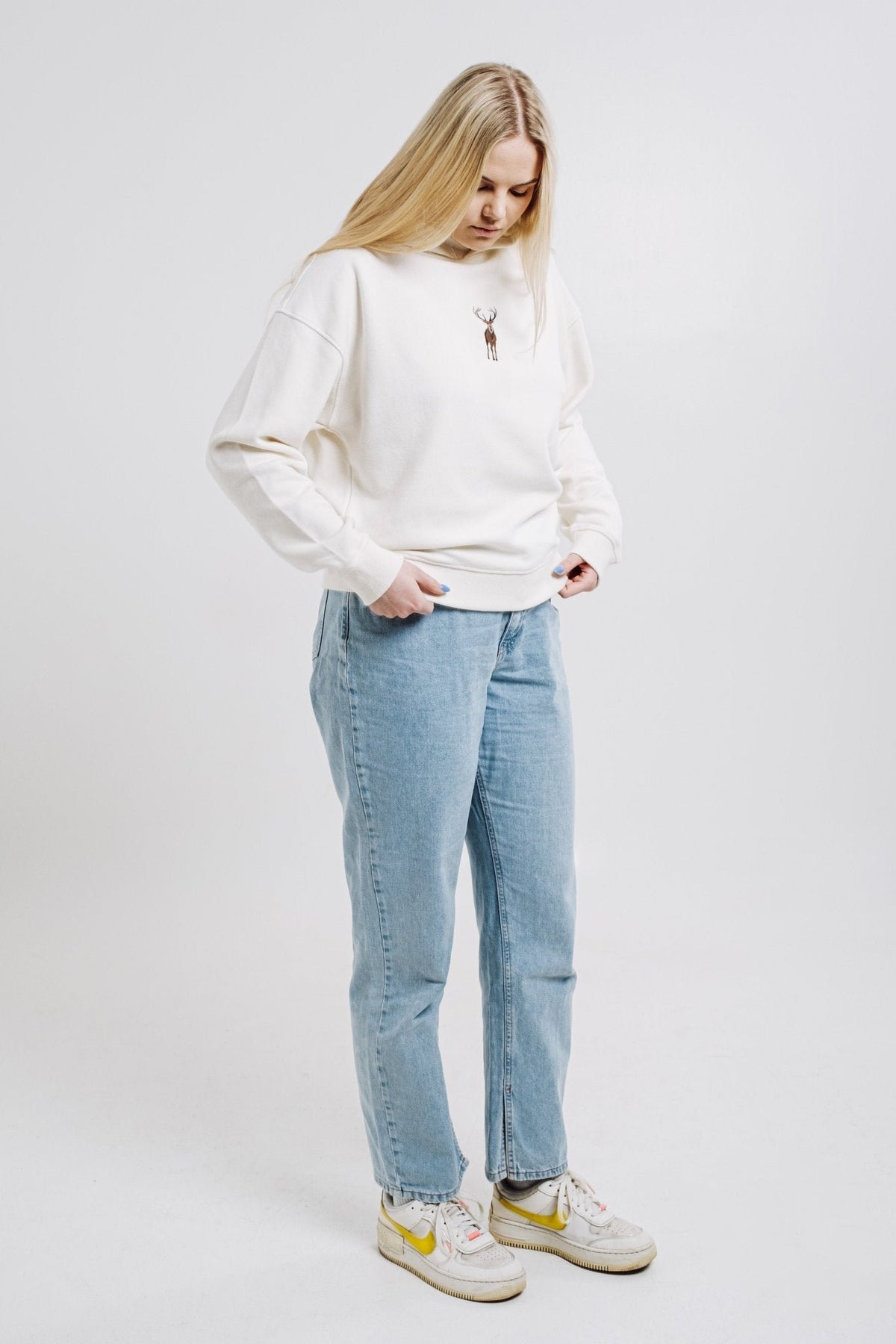 6. Woman in cream Sossu Deer Hoodie with embroidered deer, styled casually with jeans in studio