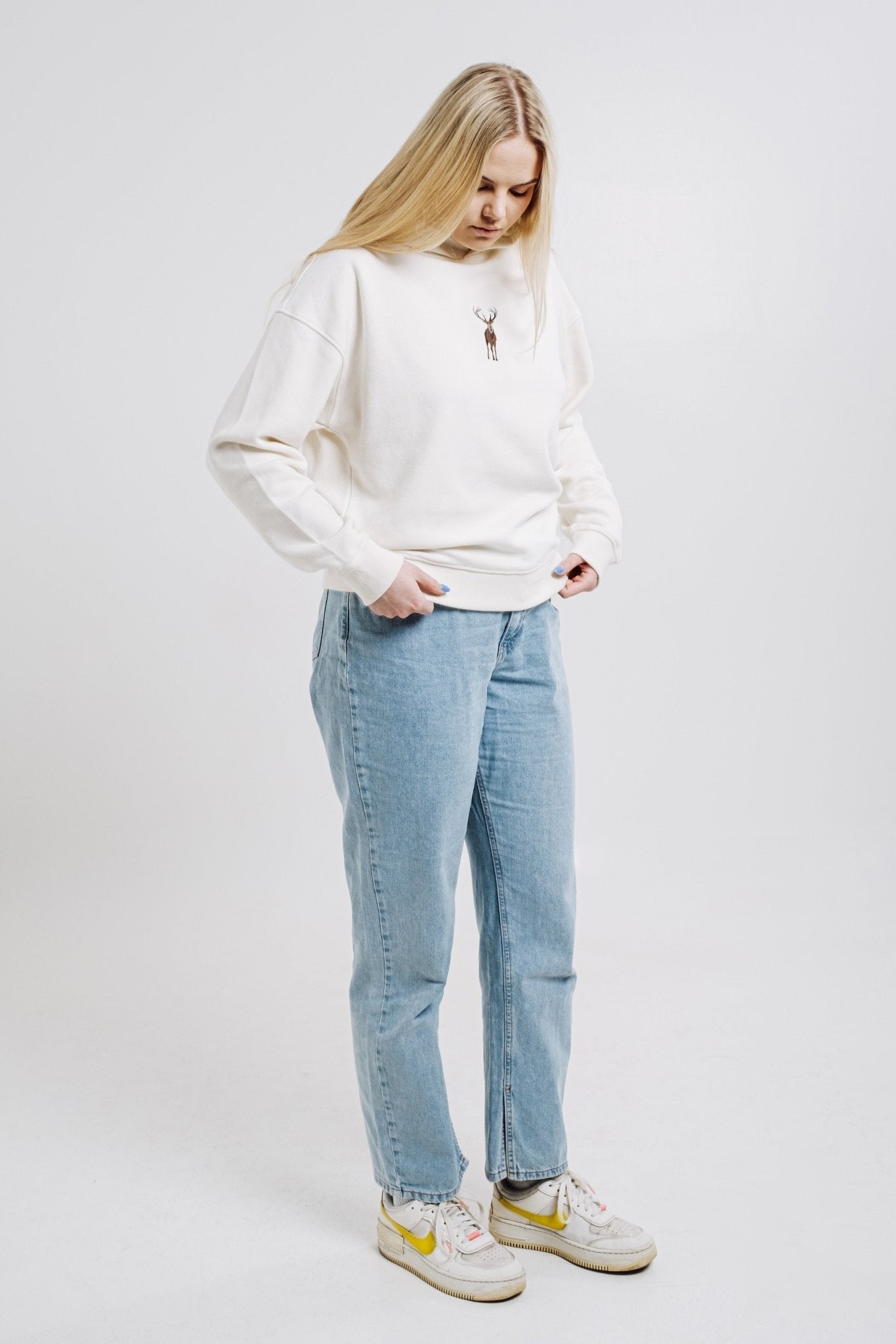 6. Woman in cream Sossu Deer Hoodie with embroidered deer, styled casually with jeans in studio