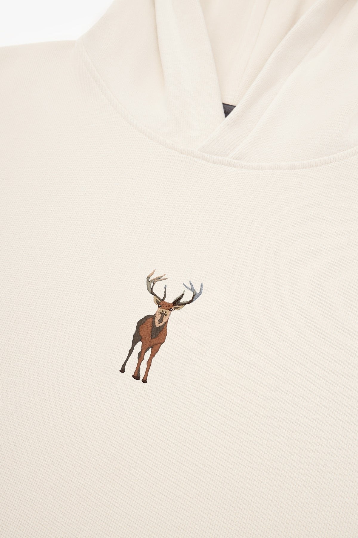 4. Close-up of embroidered deer on cream Sossu Deer Hoodie fabric