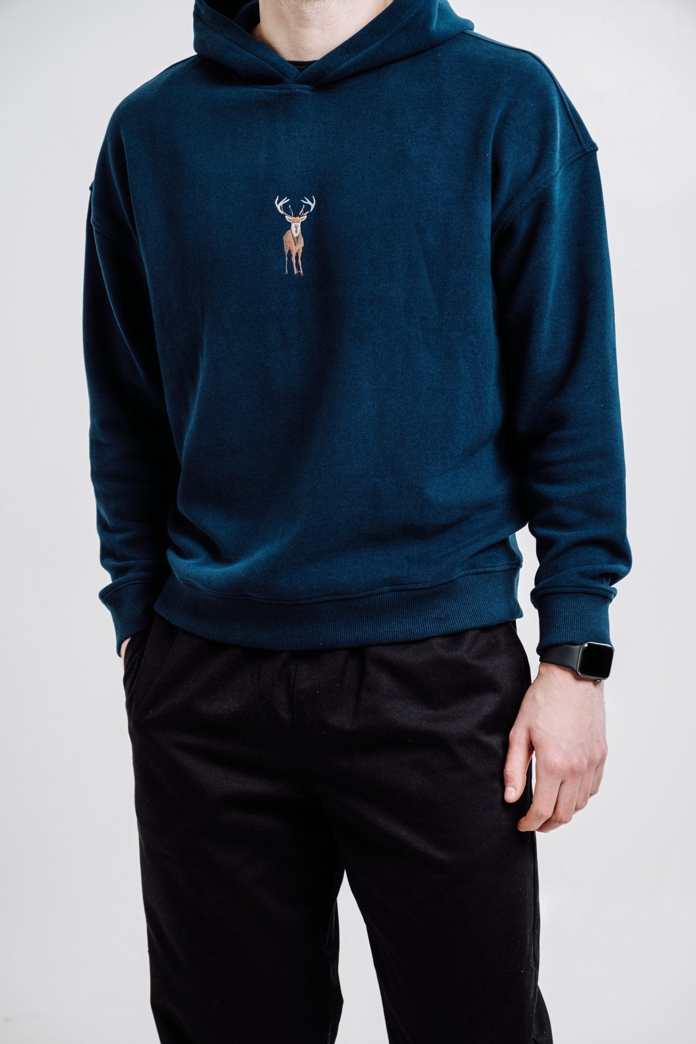 1. Unisex Deer Hoodie in Indigo Blue worn by male model, showcasing relaxed fit and embroidered design