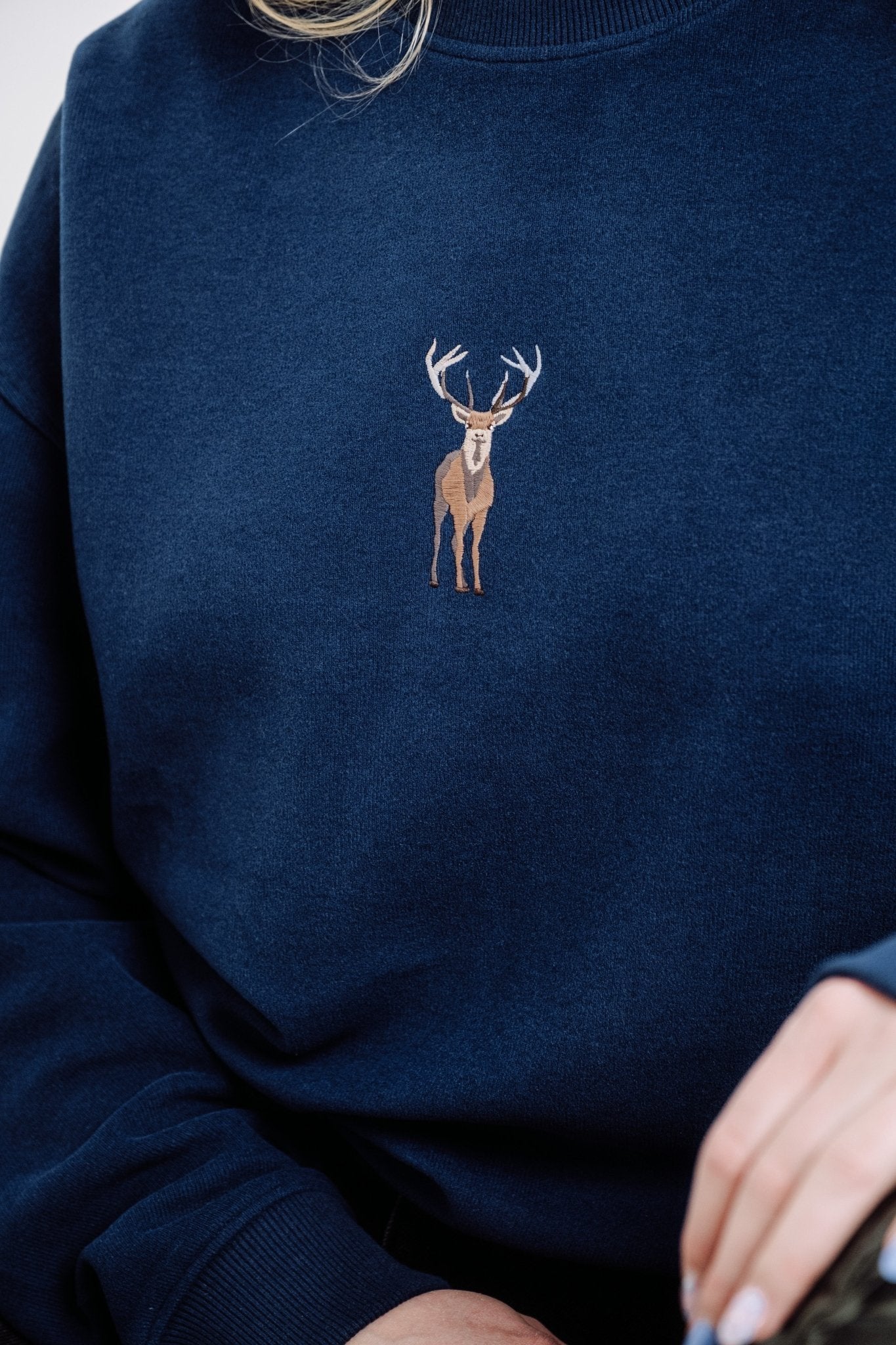 2. Close-up of unisex indigo blue Deer Sweatshirt by Sossu, highlighting embroidered deer design