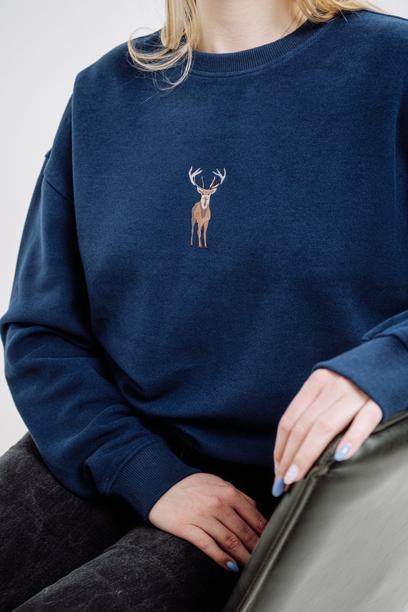 1. Unisex indigo blue Deer Sweatshirt by Sossu worn by female model, showcasing embroidered deer design