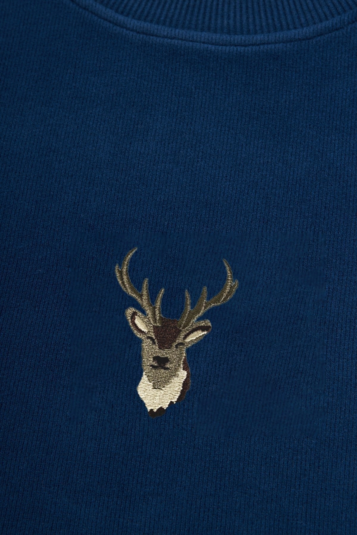 4. Detailed close-up of embroidered deer design on indigo blue fabric of Sossu sweatshirt