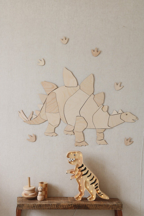1. Wooden stegosaurus wall decoration with puzzle design and extra footprints on beige wall above wooden toys