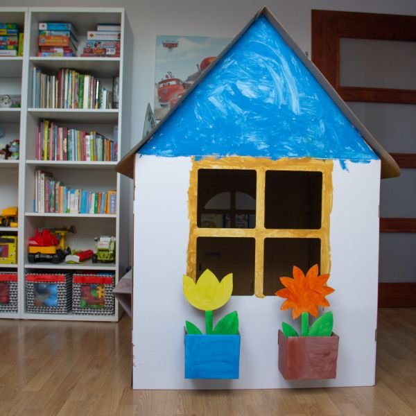 2. Decorated SEIK cardboard playhouse for kids with blue roof and flower pots, displayed indoors