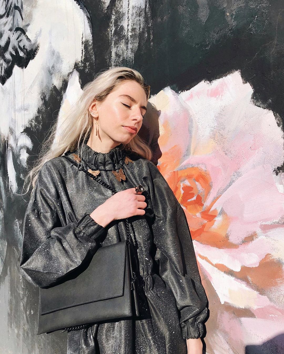 3. Woman posing with RR black matte leather chain shoulder bag in outdoor setting