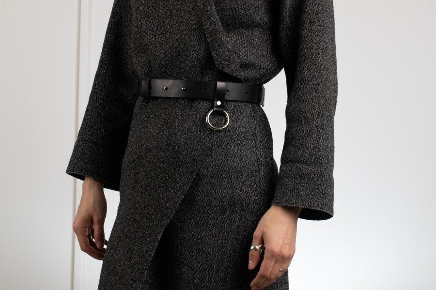1. Unisex black leather Oslo belt by PYKOK worn by a model, featuring O ring snap hook and adjustable closure, styled with a dark outfit