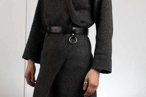 1. Unisex black leather Oslo belt by PYKOK worn by a model, featuring O ring snap hook and adjustable closure, styled with a dark outfit