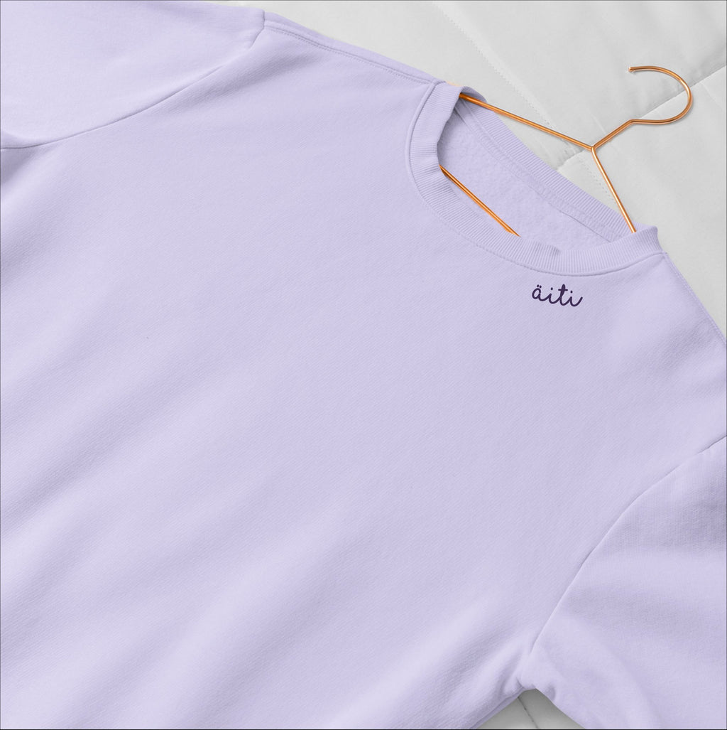 3. Unisex lilac Äiti sweatshirt with embroidered collar, laid flat on a bed