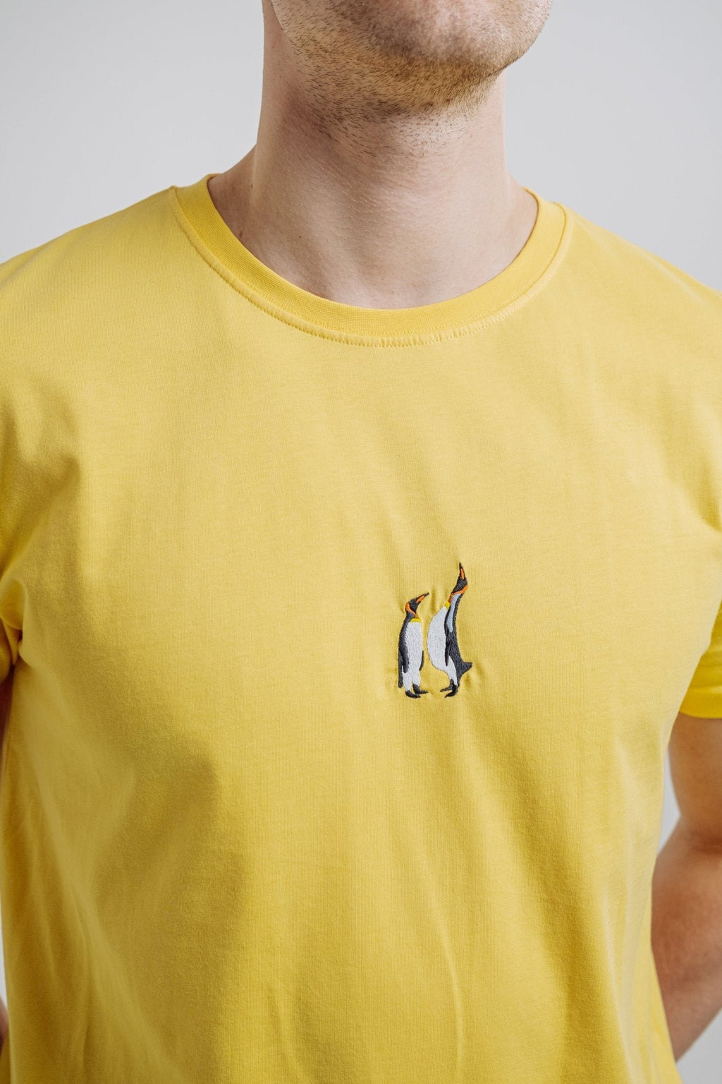 3. Close-up of embroidered penguin design on yellow Emperor Penguin T-shirt by Sossu