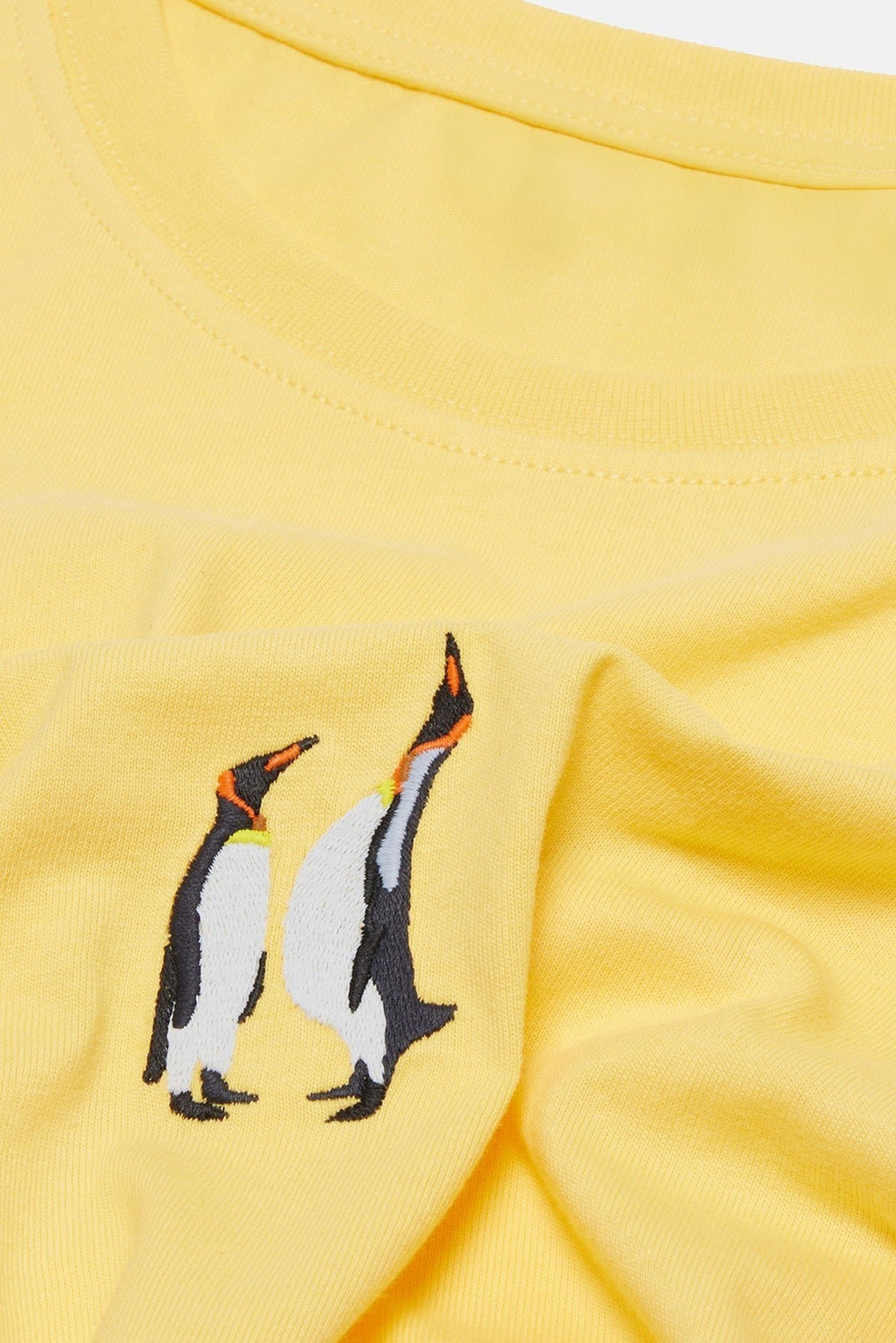 6. Close-up of embroidered penguin design on yellow cotton fabric of Emperor Penguin T-shirt