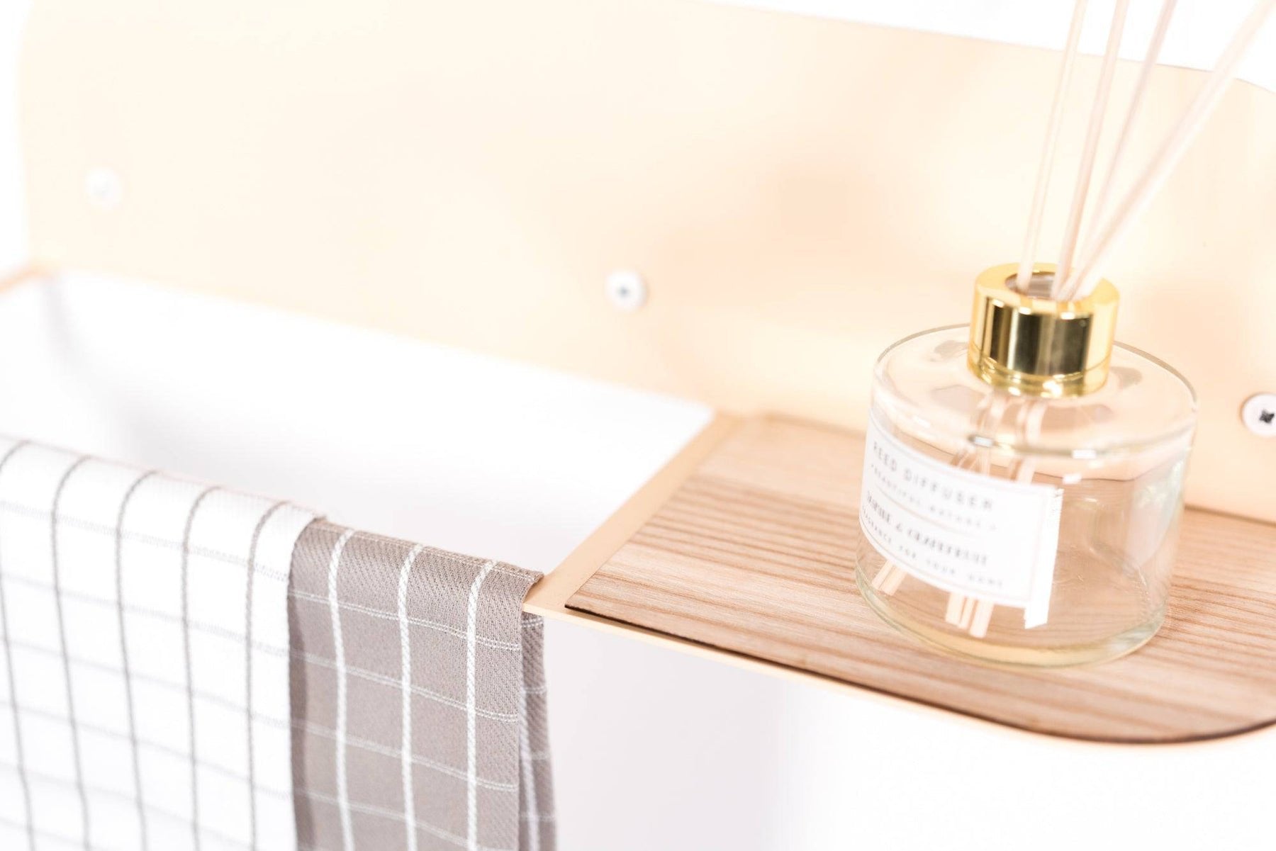 3. Detailed view of wooden shelf on beige towel rack with diffuser and checkered towel