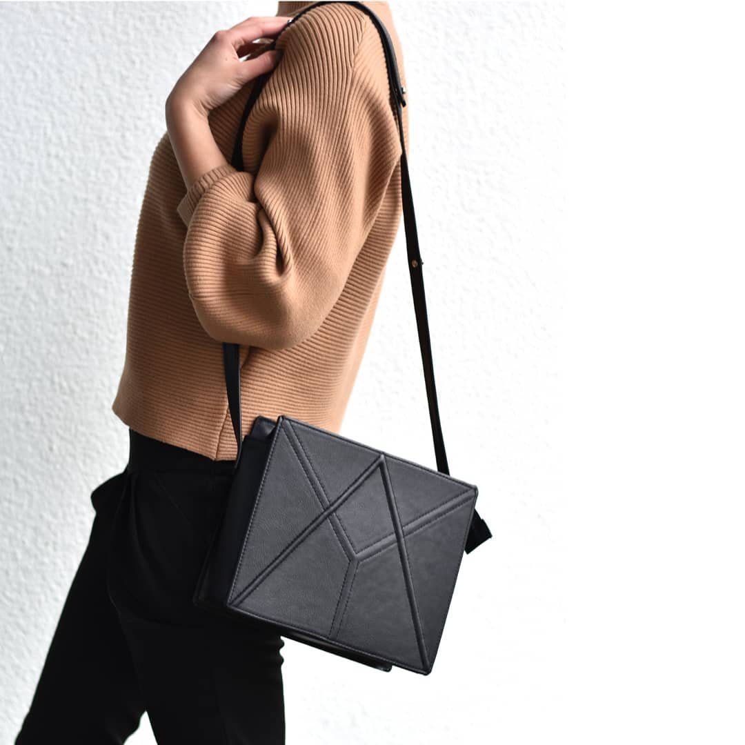 1. Women's black FACET shoulder bag by Gerda Retter Design worn crossbody, showcasing adjustable strap and geometric design