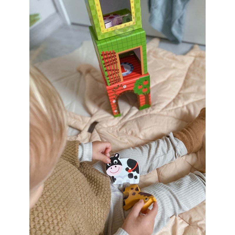 9. Child holding cow and giraffe figurines next to colorful cubes on a beige surface