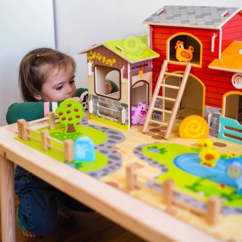 1. Child playing with Woopie Green Mega Farm set on a table, featuring barn, stable, and animal figurines in a playroom setting