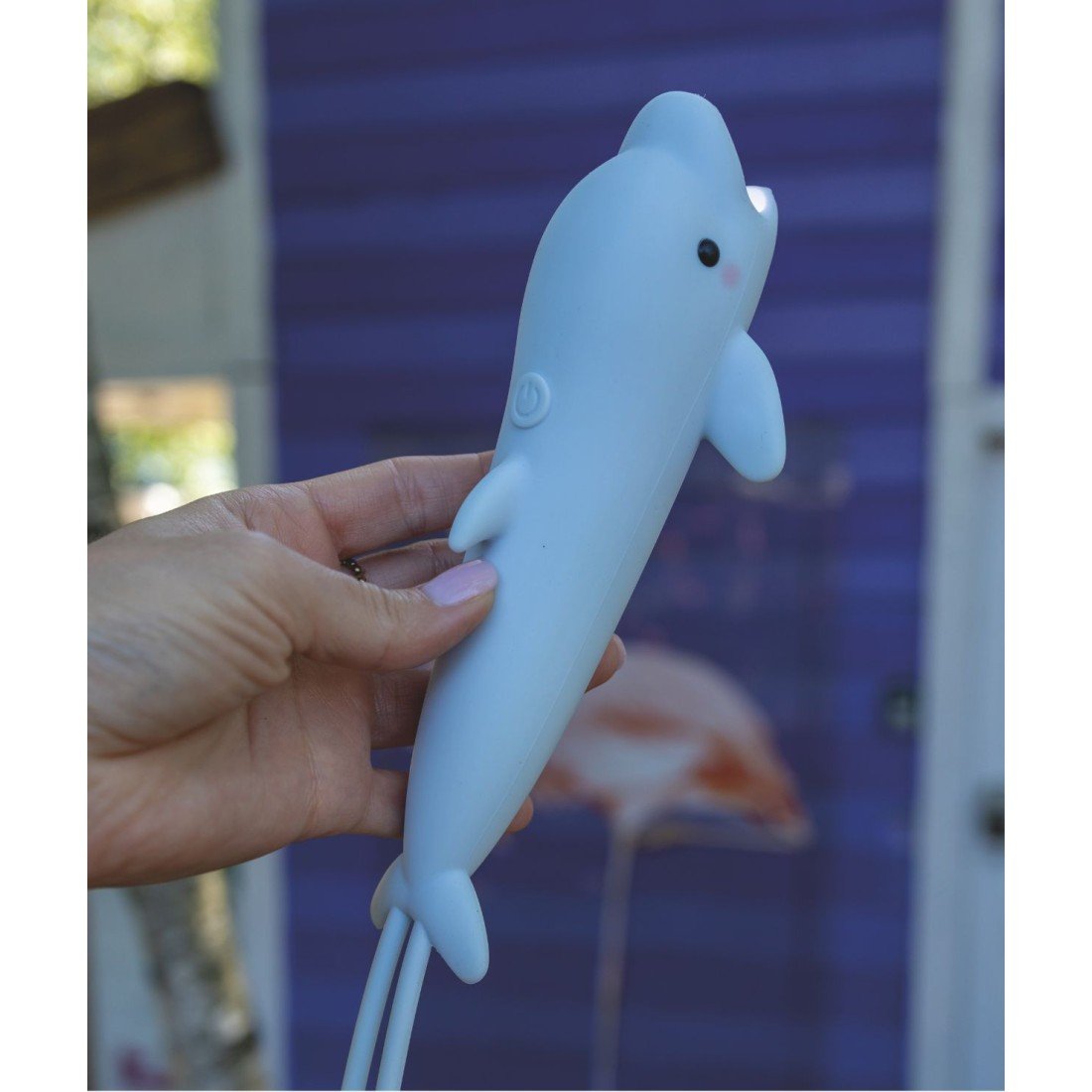 1. Hand holding a blue dolphin-shaped flashlight against a purple background outdoors