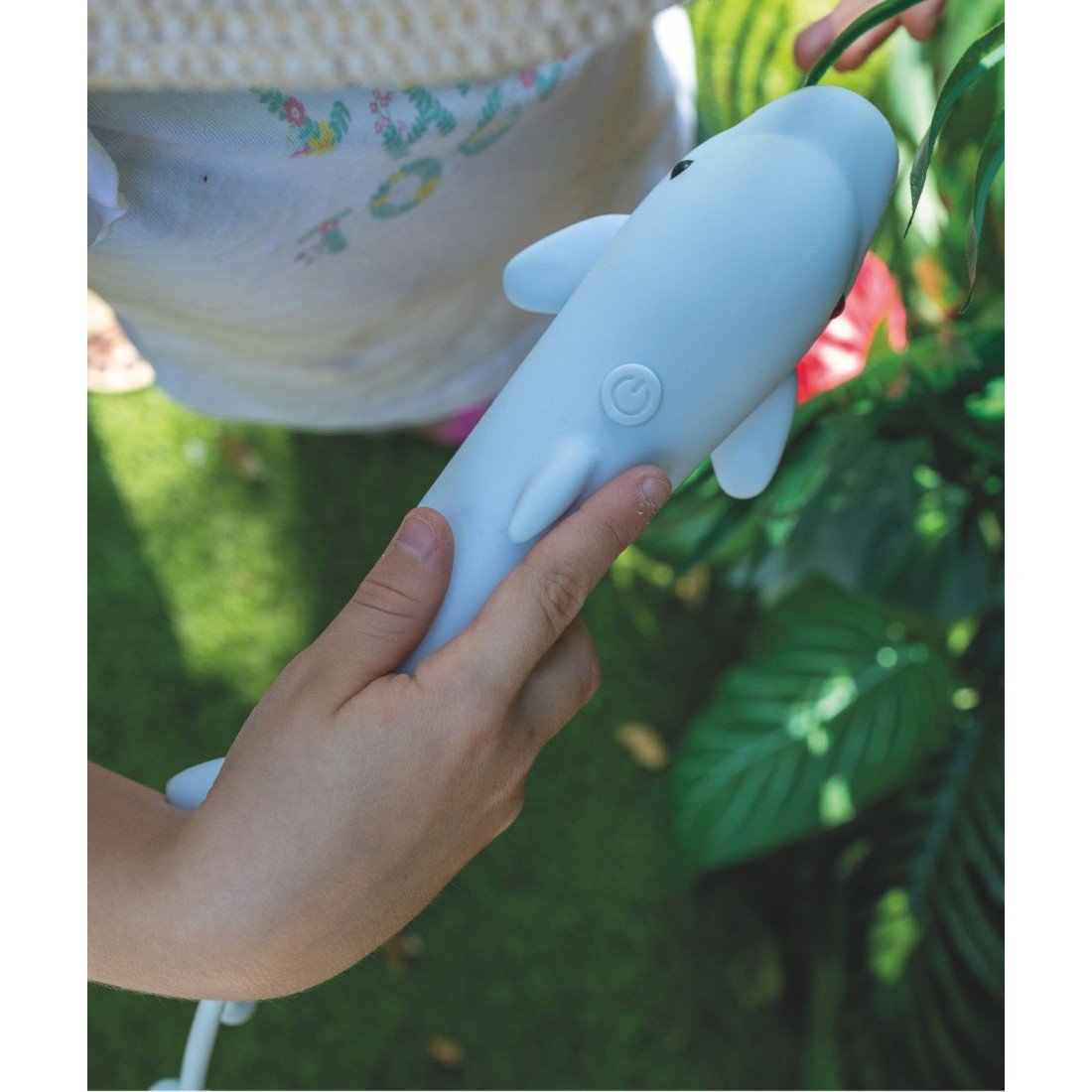 1. Child holding a blue dolphin-shaped flashlight with visible power button, surrounded by greenery