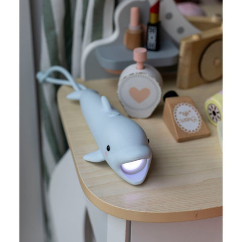 1. Blue dolphin-shaped flashlight on a wooden table with decorative items, light turned on