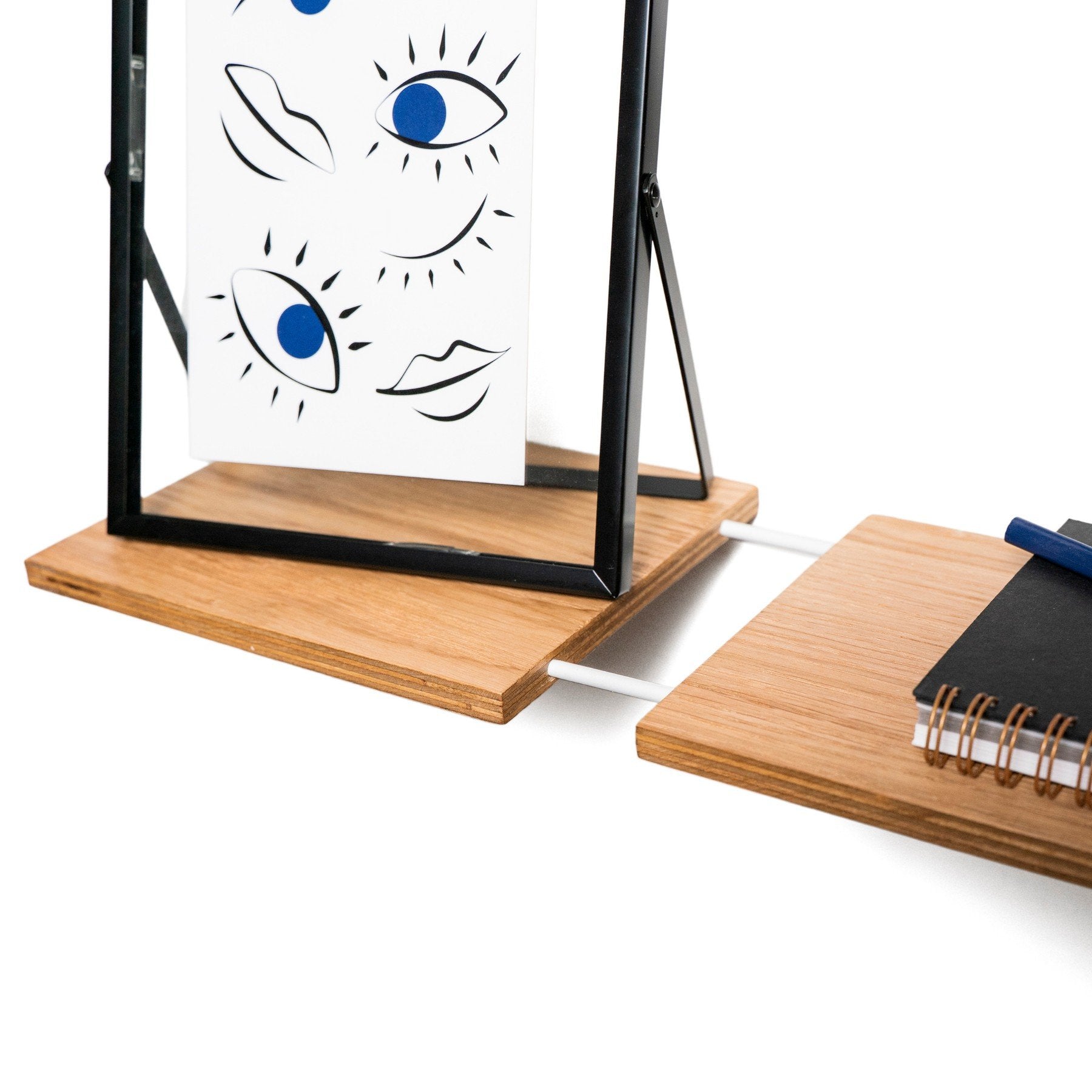 7. Close-up of framed artwork and notebook on wooden wall shelf, showcasing Baltic birch plywood construction and modern design.