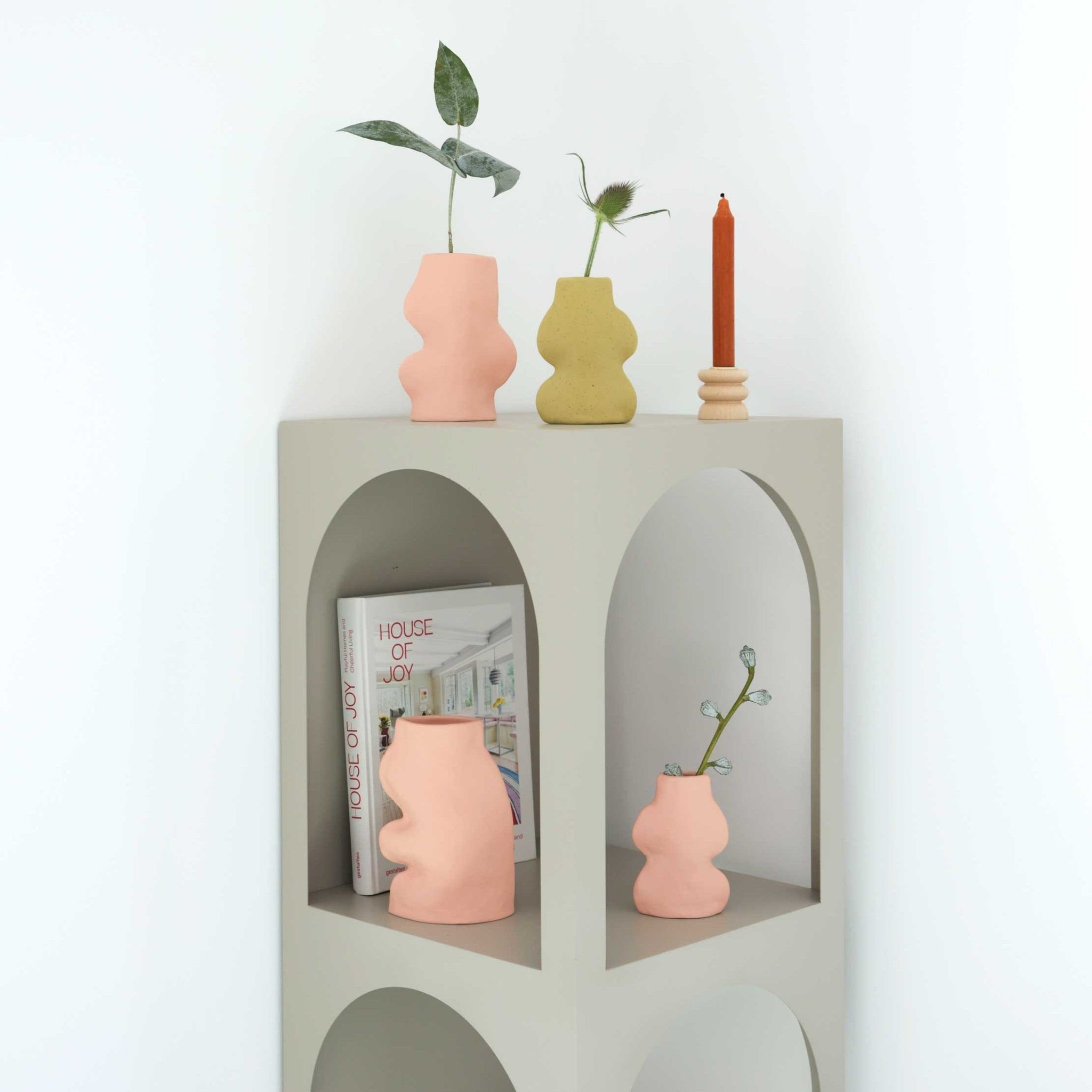 3. Fluxo Ceramic Vase in pink and other colors styled on a shelf, demonstrating versatile decorating options