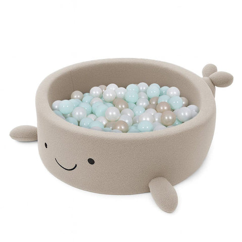 2. Beige whale-shaped foam baby ball pit filled with pastel-colored balls, featuring soft boucle finish and smiling face