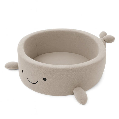 1. Beige whale-shaped foam baby ball pit with soft boucle finish and smiling face, shown empty on white background