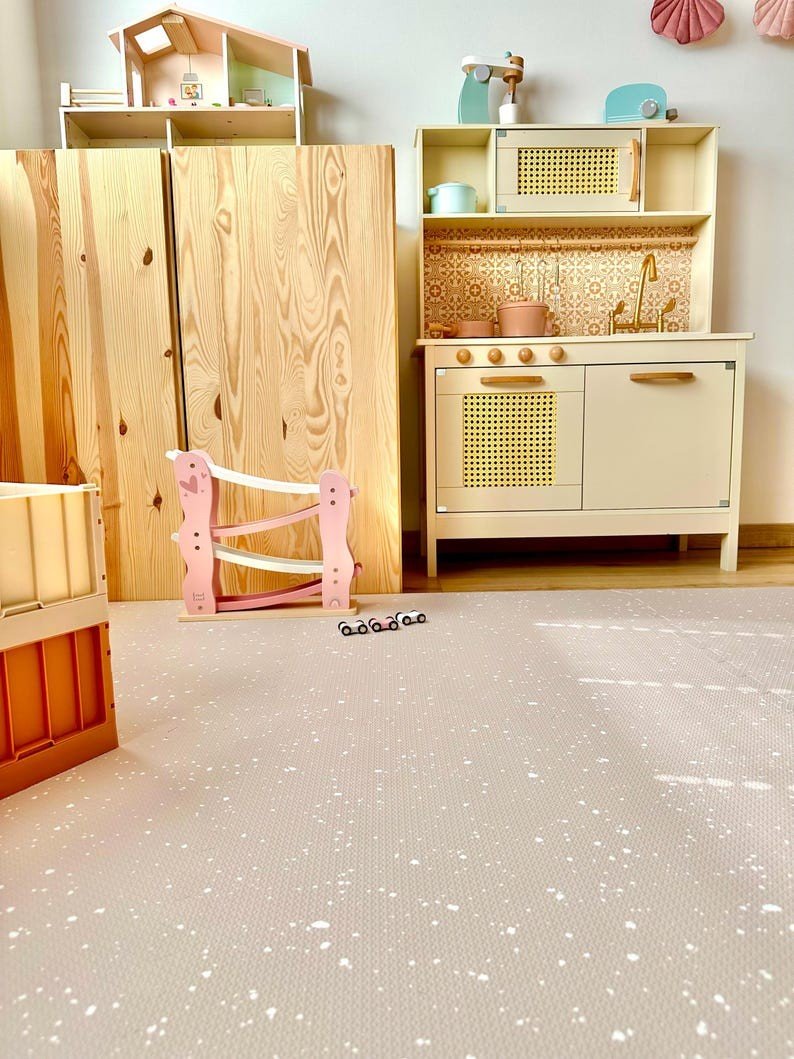 2. Children's playroom with cappuccino foam puzzle playmat, wooden kitchen set, and pink toy rail