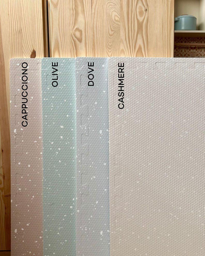 7. Vertical display of foam puzzle playmats in cappuccino, olive, dove, and cashmere against wooden background