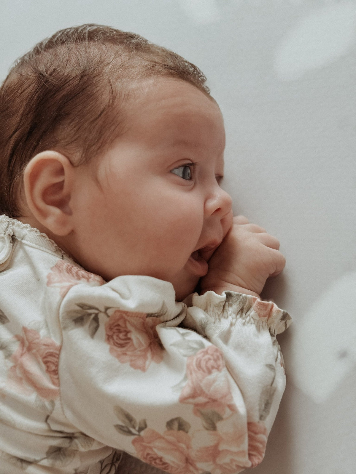 7. Baby in floral outfit on lavender terrazzo playmat sucking thumb