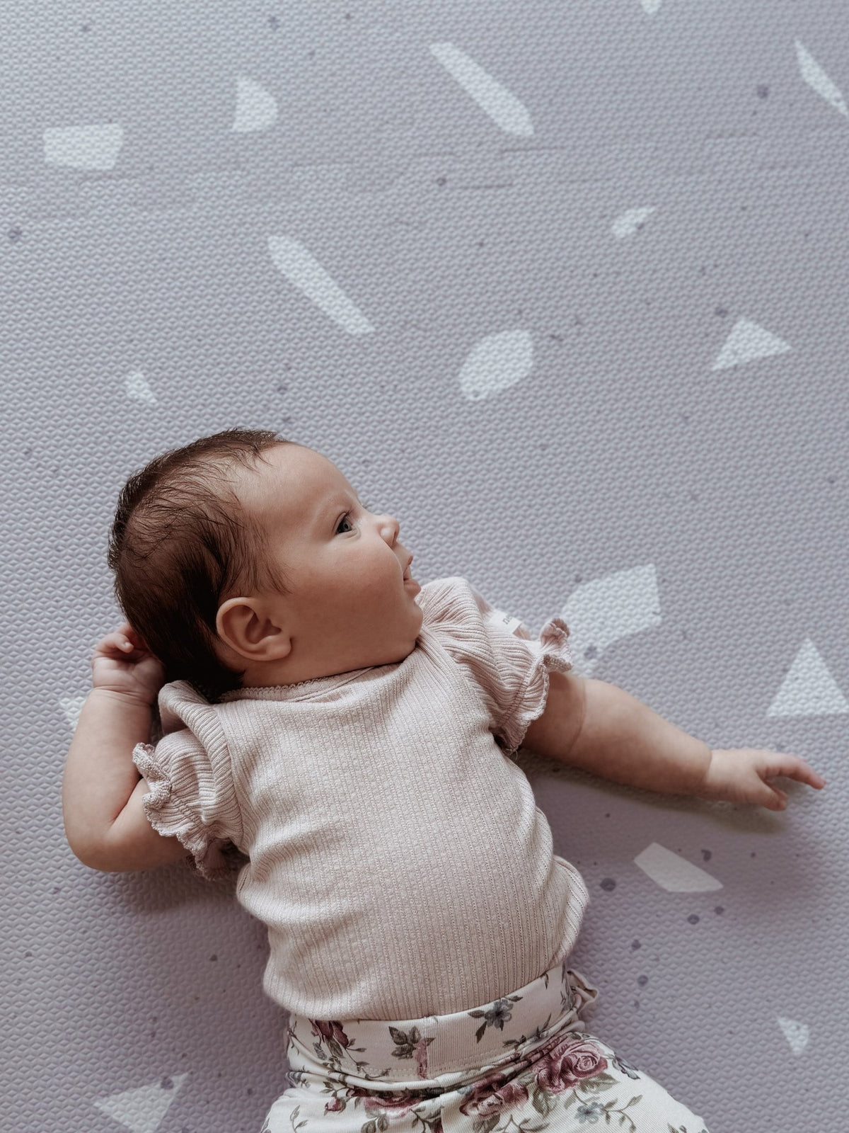 2. Baby in pink top on lavender terrazzo playmat looking to the side